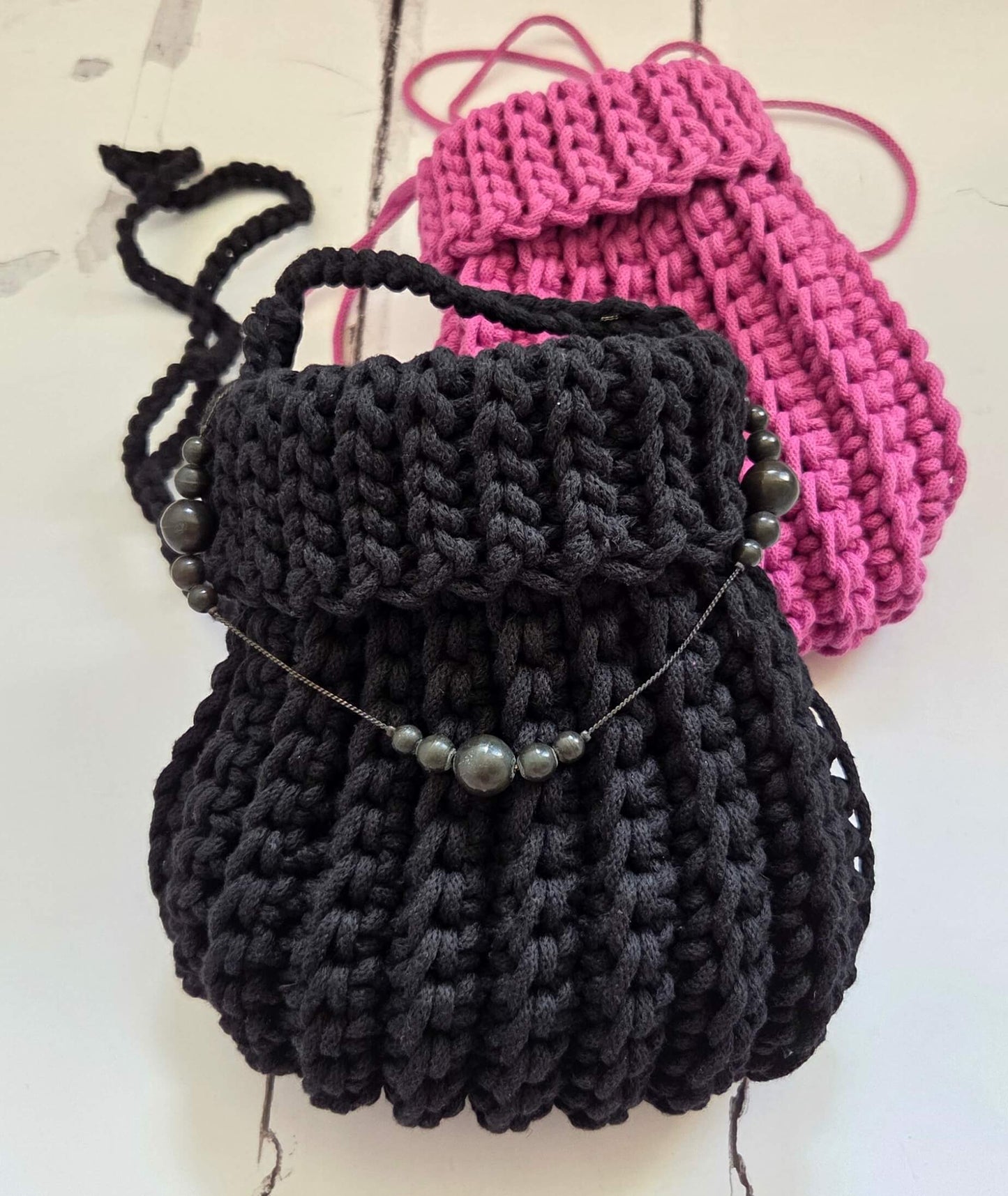Black and pink knitted drawstring bags on a light background