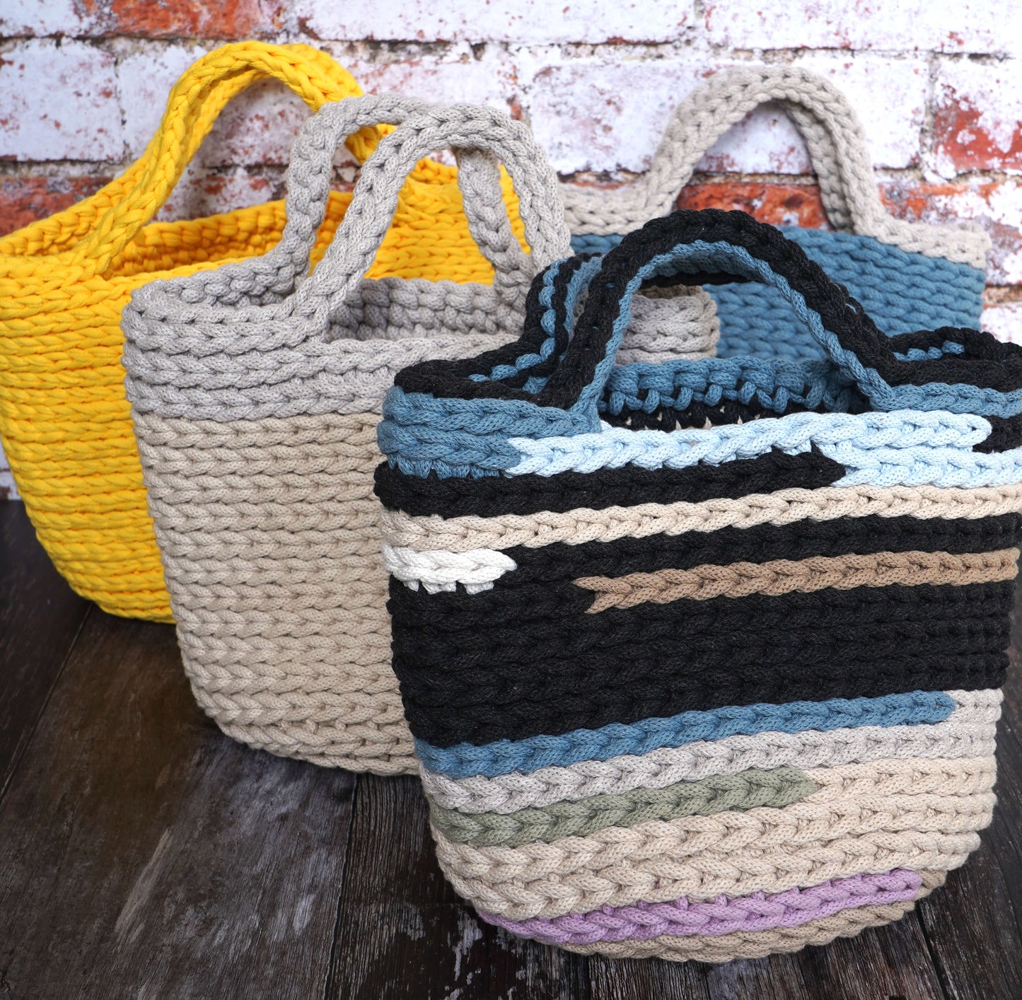 Three woven baskets in different colors on a wooden surface with a rustic background.
