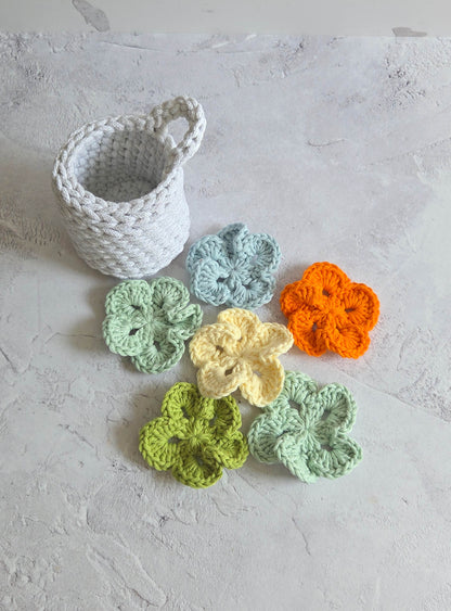 Crocheted flowers in various colors on a textured surface