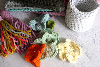 Collection of crocheted items including yarn and small flower patterns on a light surface.