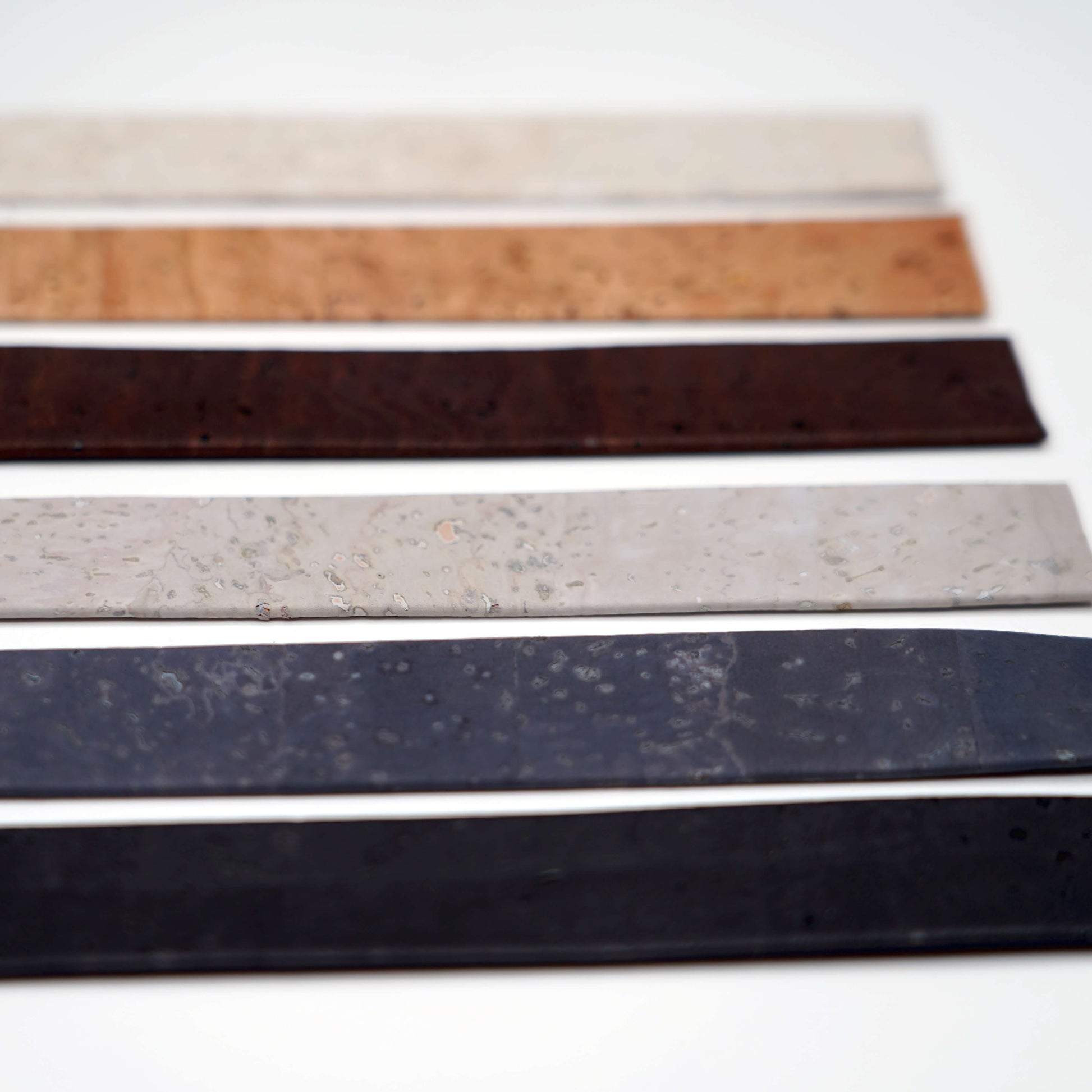 Five strips of leather in different colors on a white background
