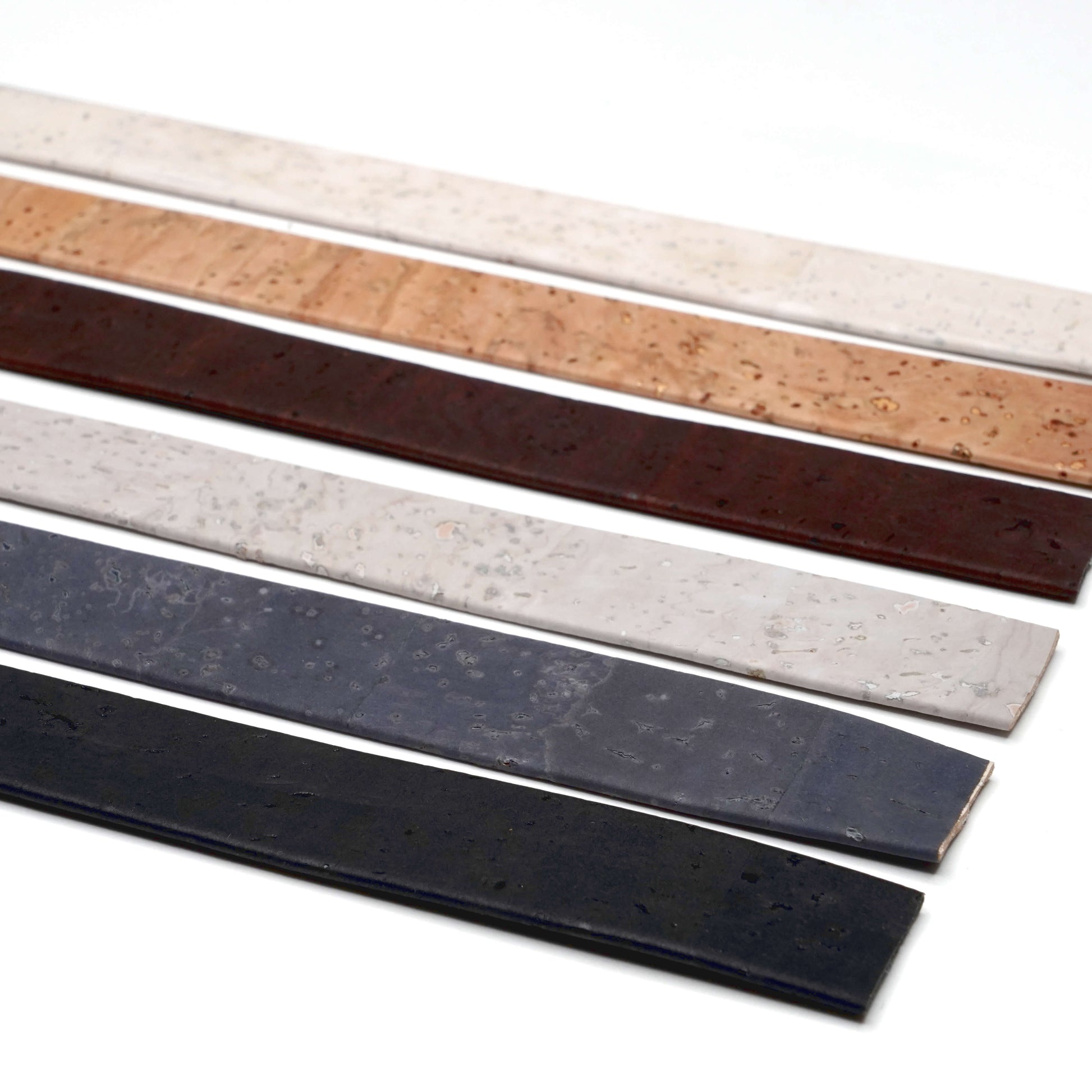 Four leather belts in different colors on a white background