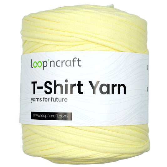 A skein of pale yellow T-shirt yarn with a white paper label that reads 'loopncraft T-Shirt Yarn' on a light gray background.