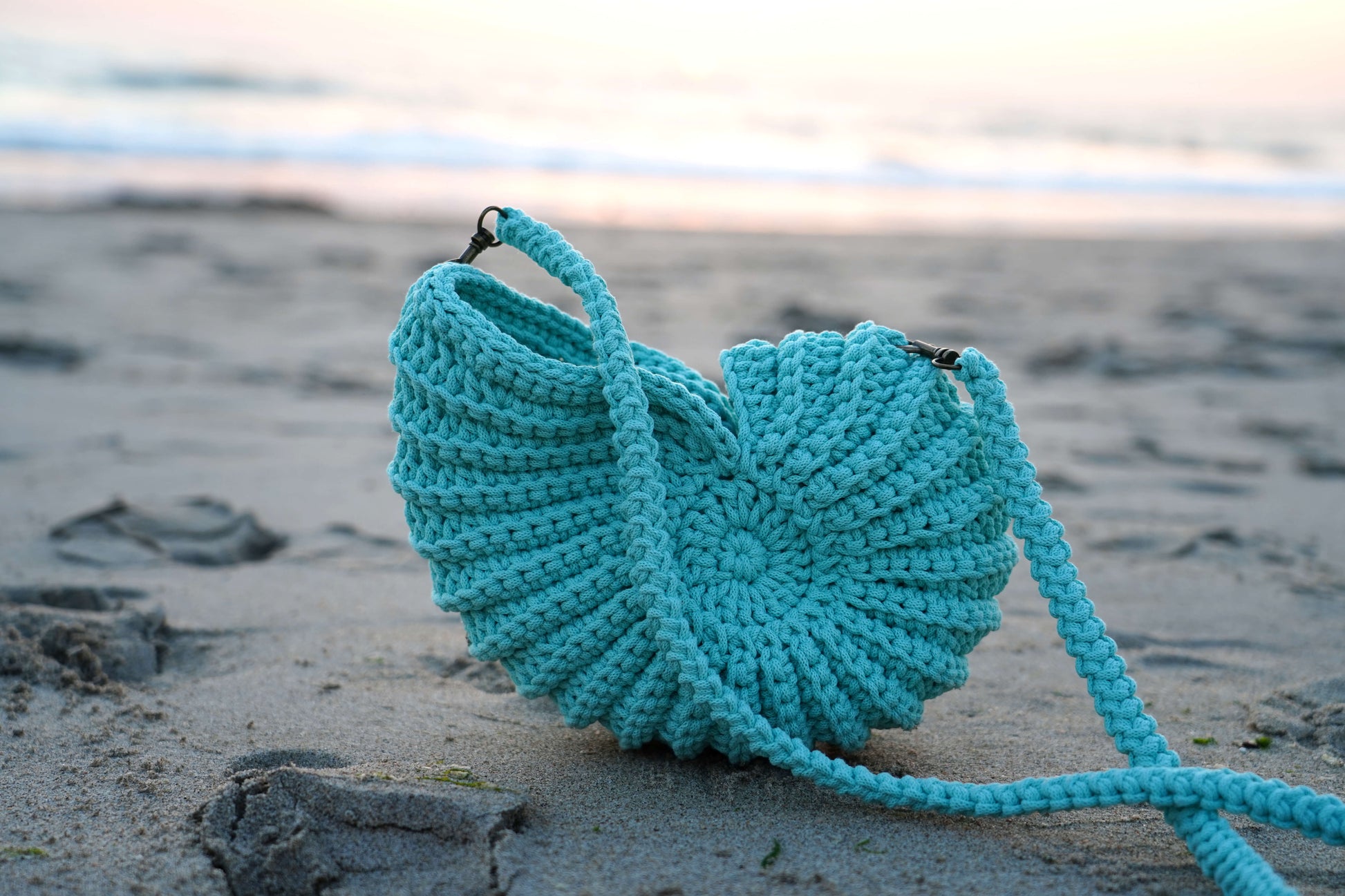 Turquoise knitted bag on a sandy beach
