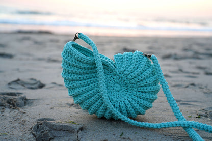 Turquoise knitted bag on a sandy beach
