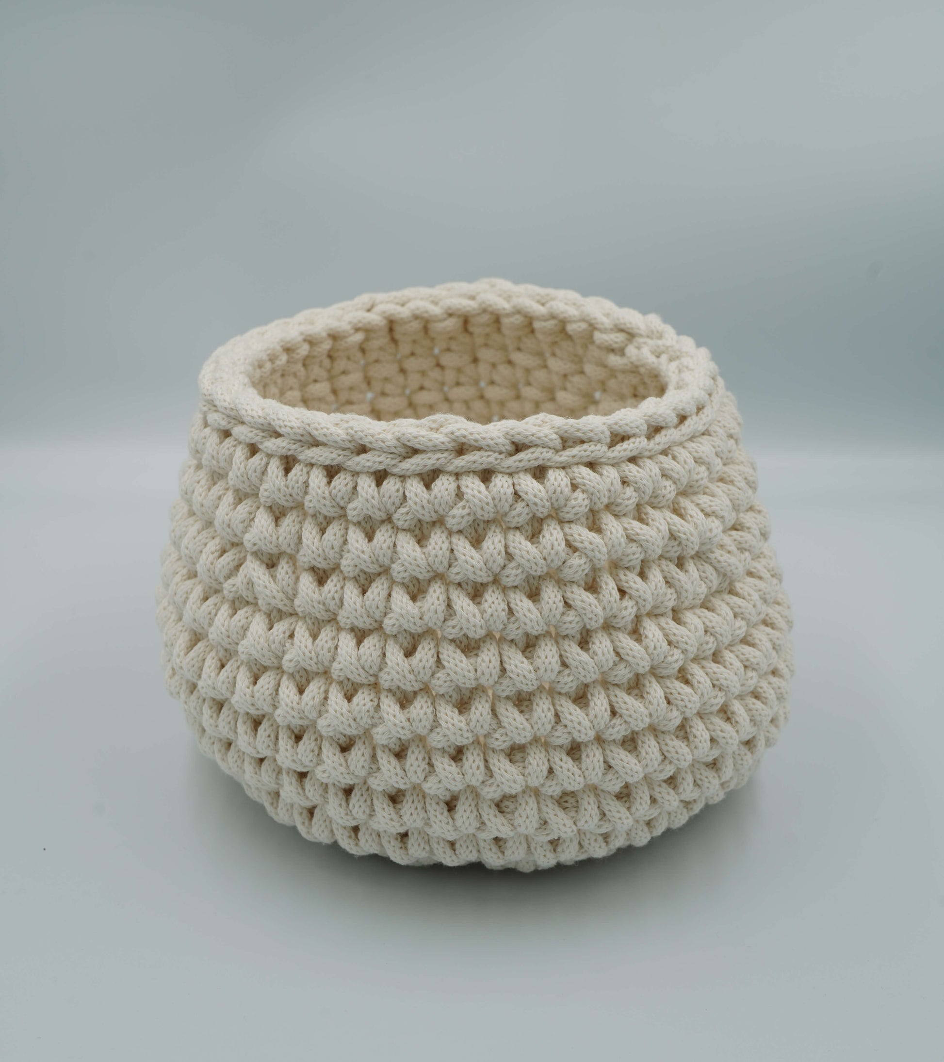 Beige crocheted basket on a light gray background