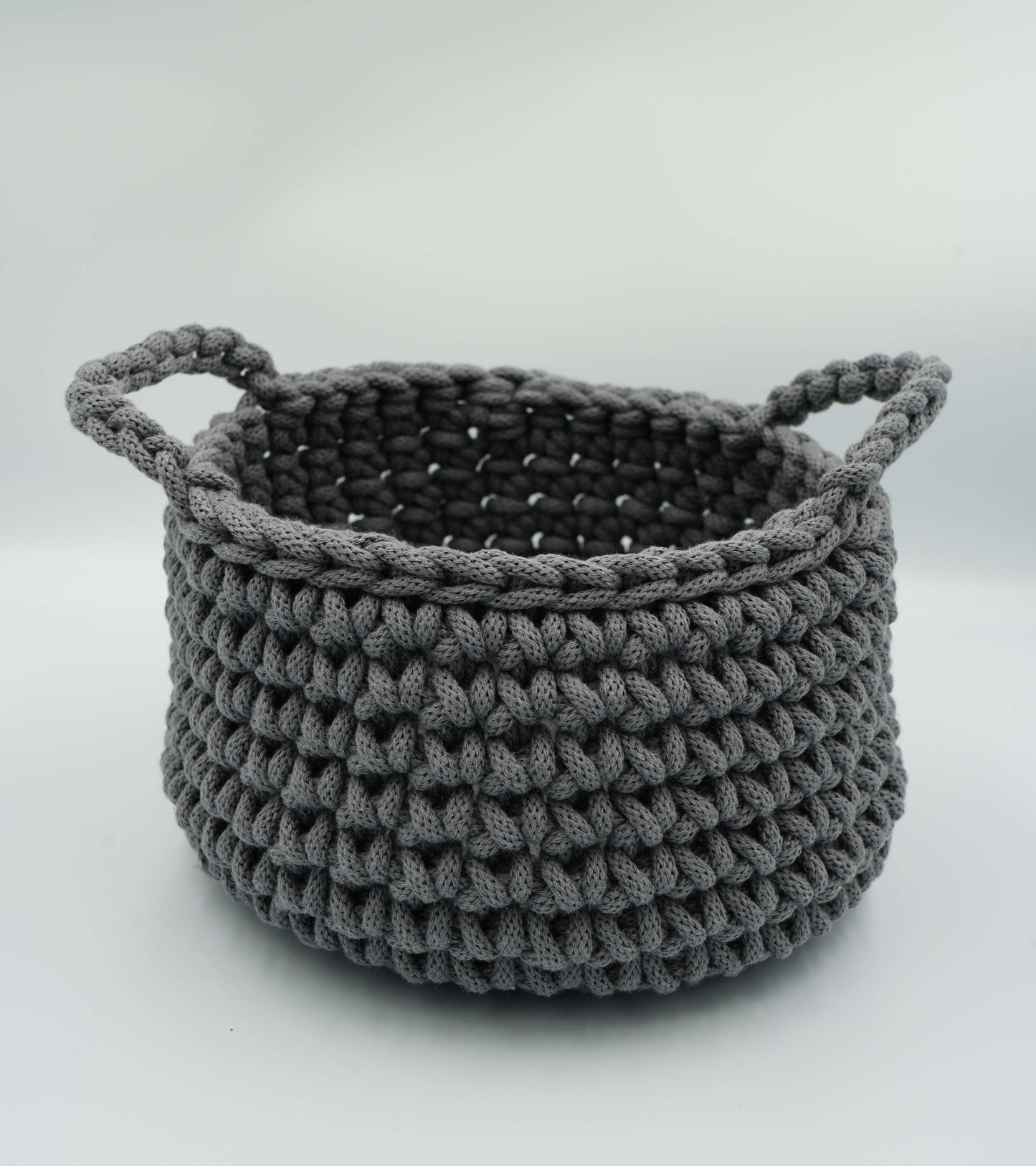Gray knitted basket with handles on a white background