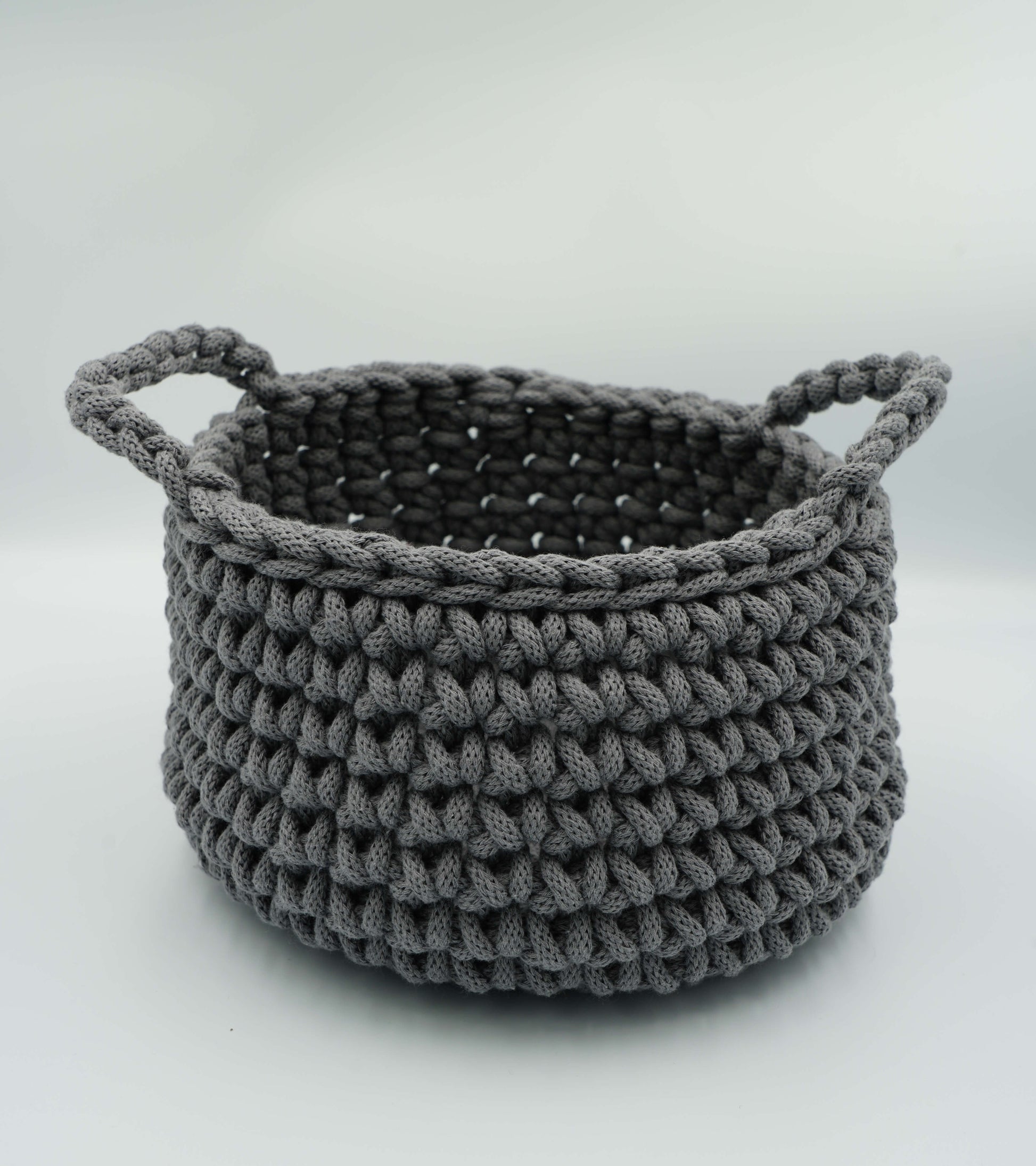 Gray knitted basket with handles on a white background