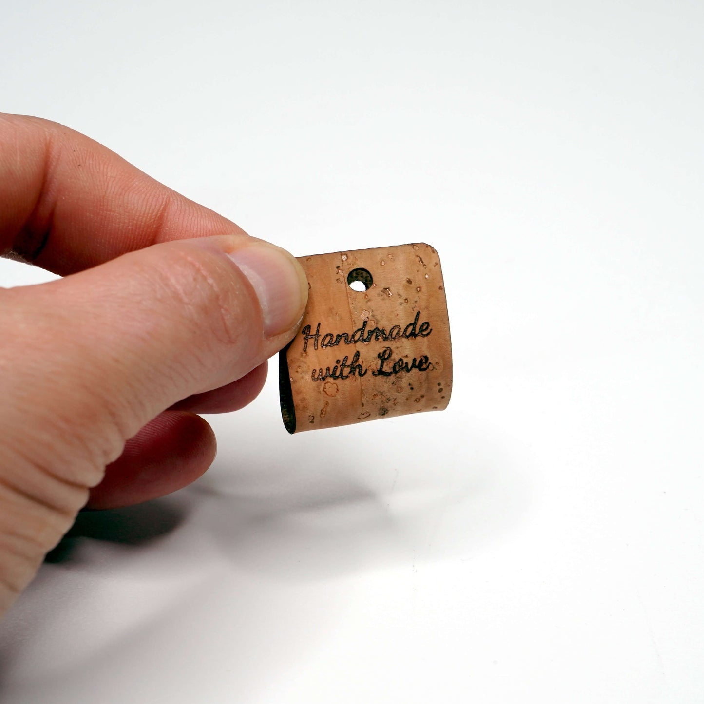 Cork with 'Handmade with Love' text held by a hand on a white background