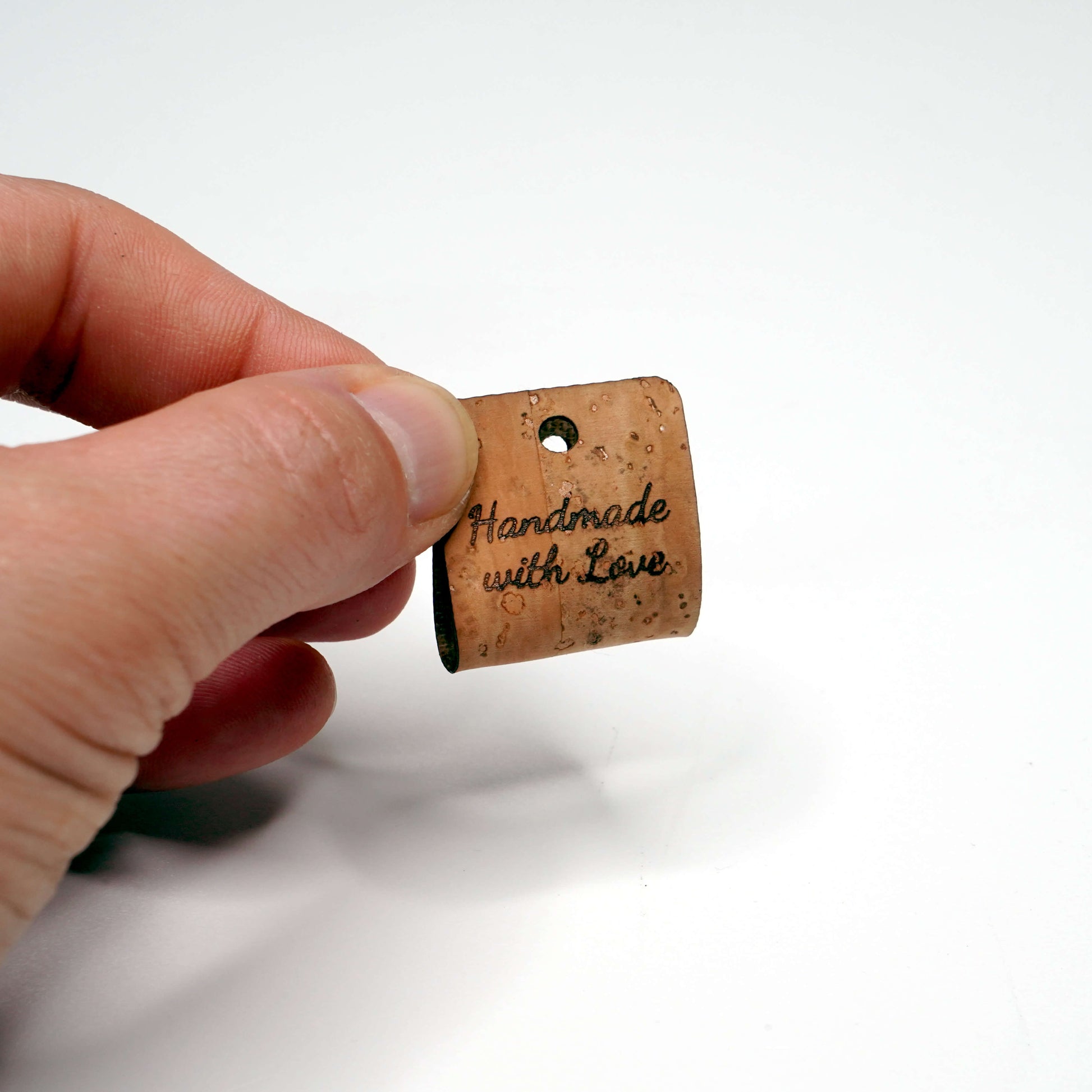 Cork with 'Handmade with Love' text held by a hand on a white background